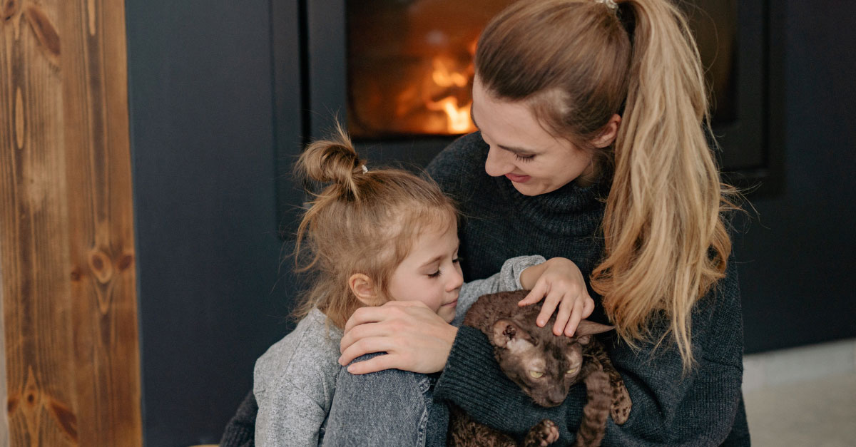 A mother and daughter cuddled up near the warm glow of a gas fireplace